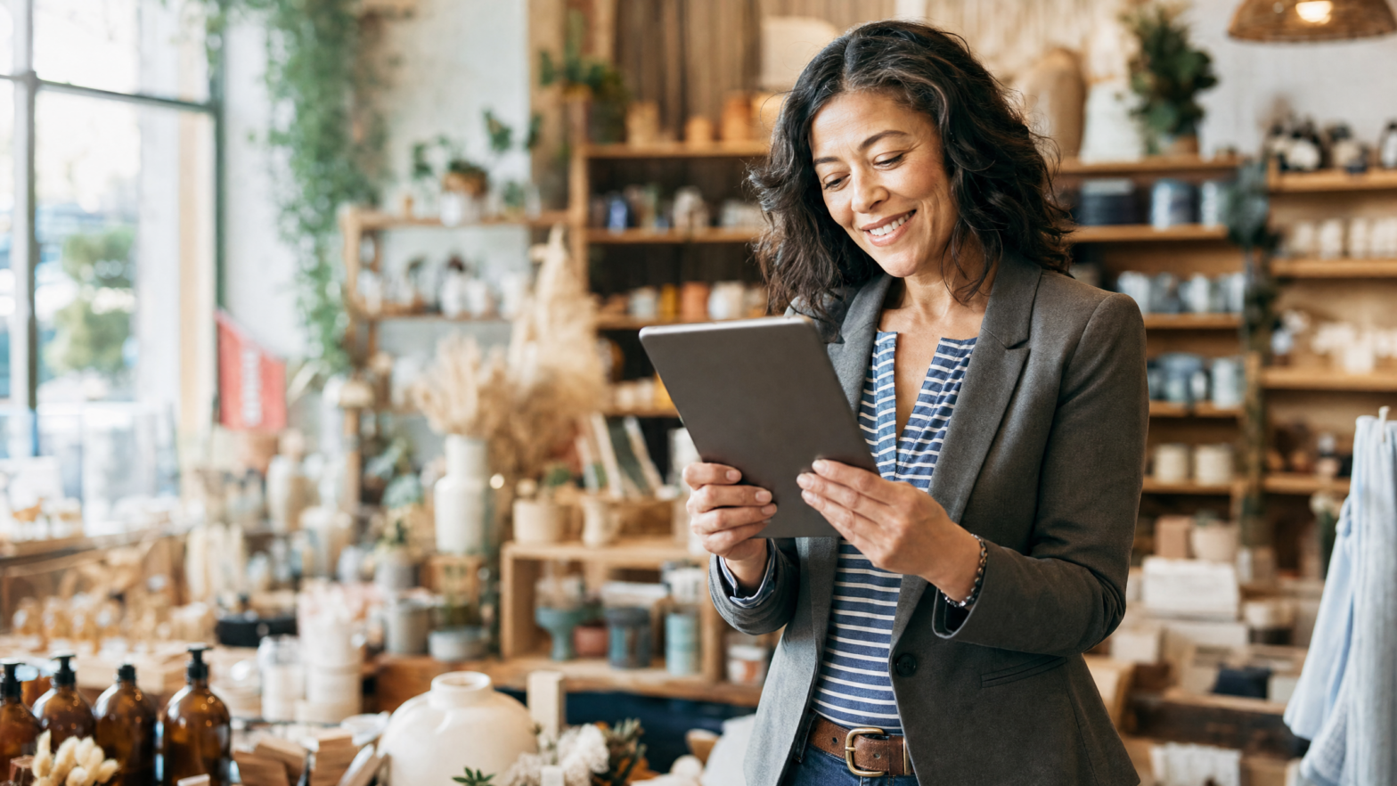 Small business owner checking their phone with a satisfied expression in their shop